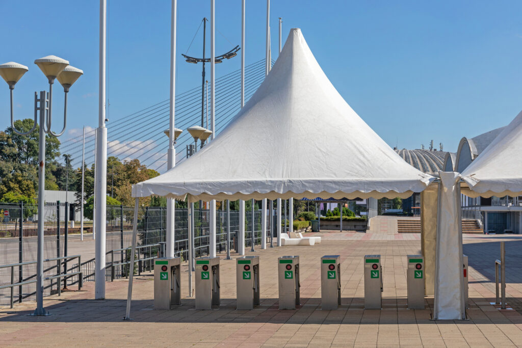 Turnstiles Covered In Shade By Tents At An Event Venue.